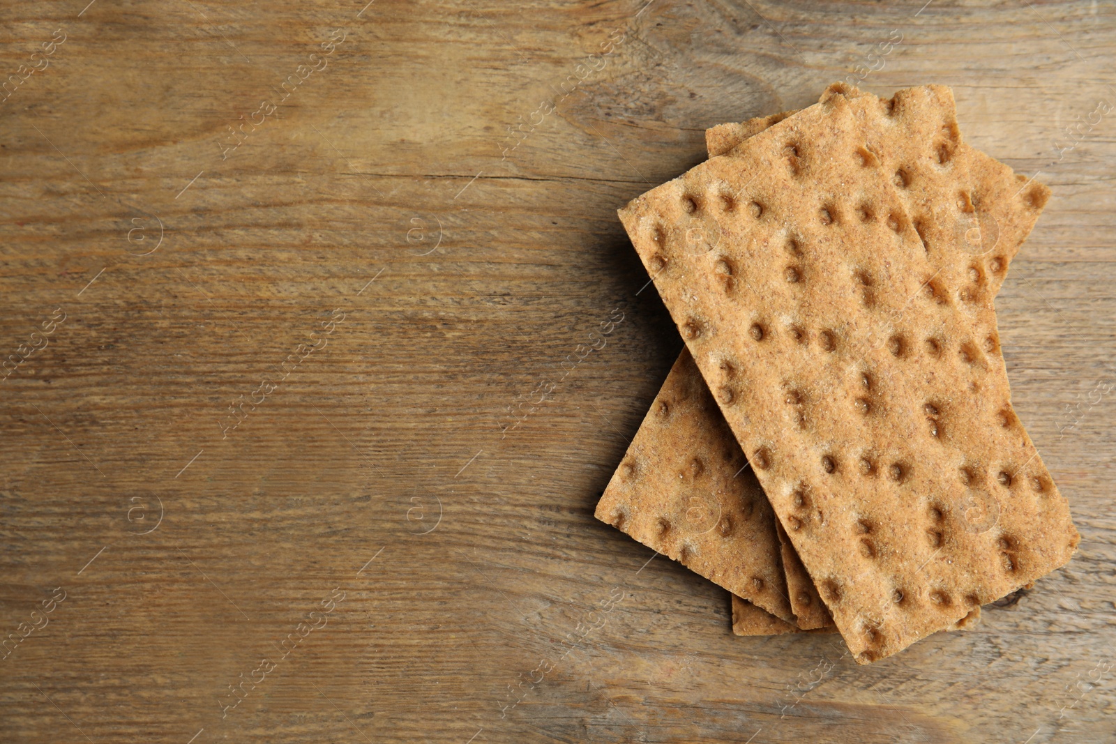 Photo of Fresh rye crispbreads on wooden table, top view. Space for text