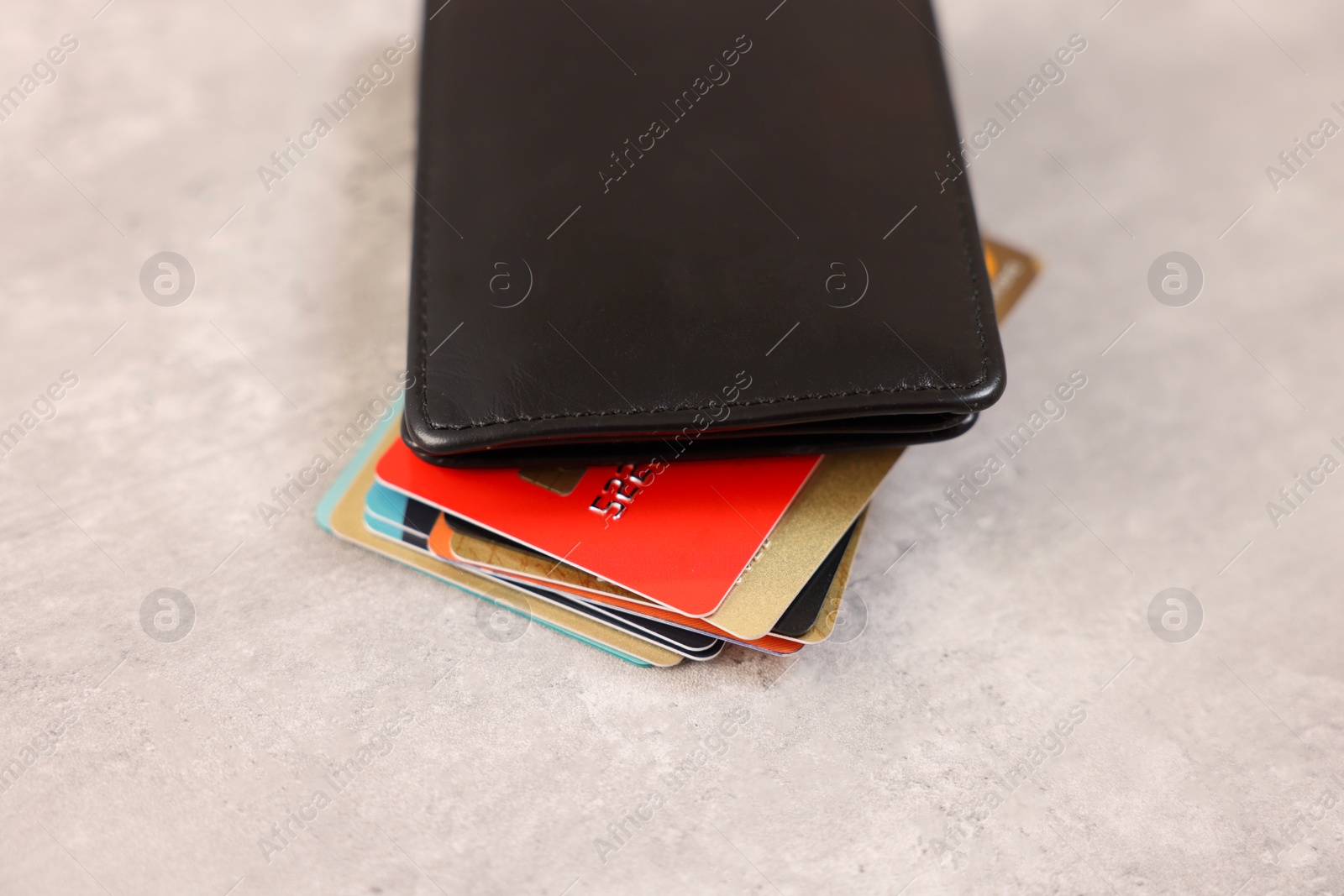 Photo of Many different credit cards and leather wallet on grey table, closeup