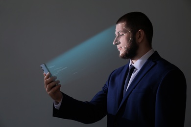 Image of Man unlocking smartphone with facial scanner on grey background. Biometric verification