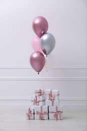 Many gift boxes and balloons near white wall in room