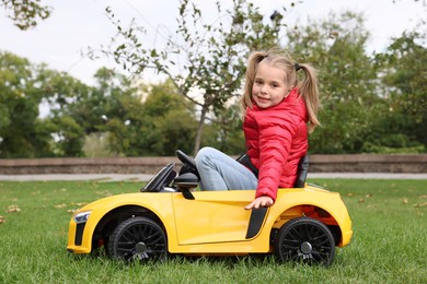 Cute little girl driving children's car in park