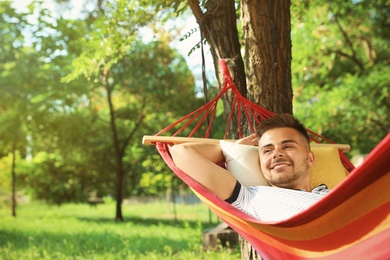 Photo of Young man resting in comfortable hammock at green garden