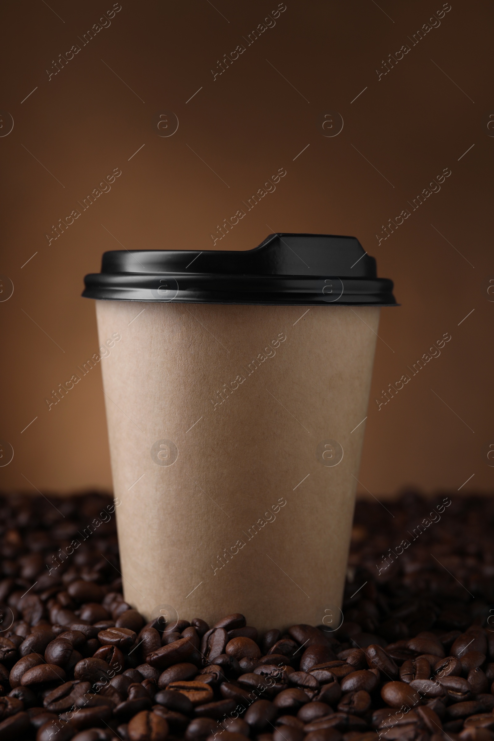 Photo of Coffee to go. Paper cup on roasted beans against brown background