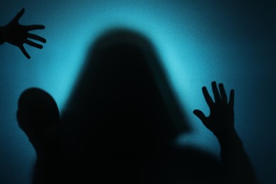 Photo of Silhouette of ghosts behind glass against blue background