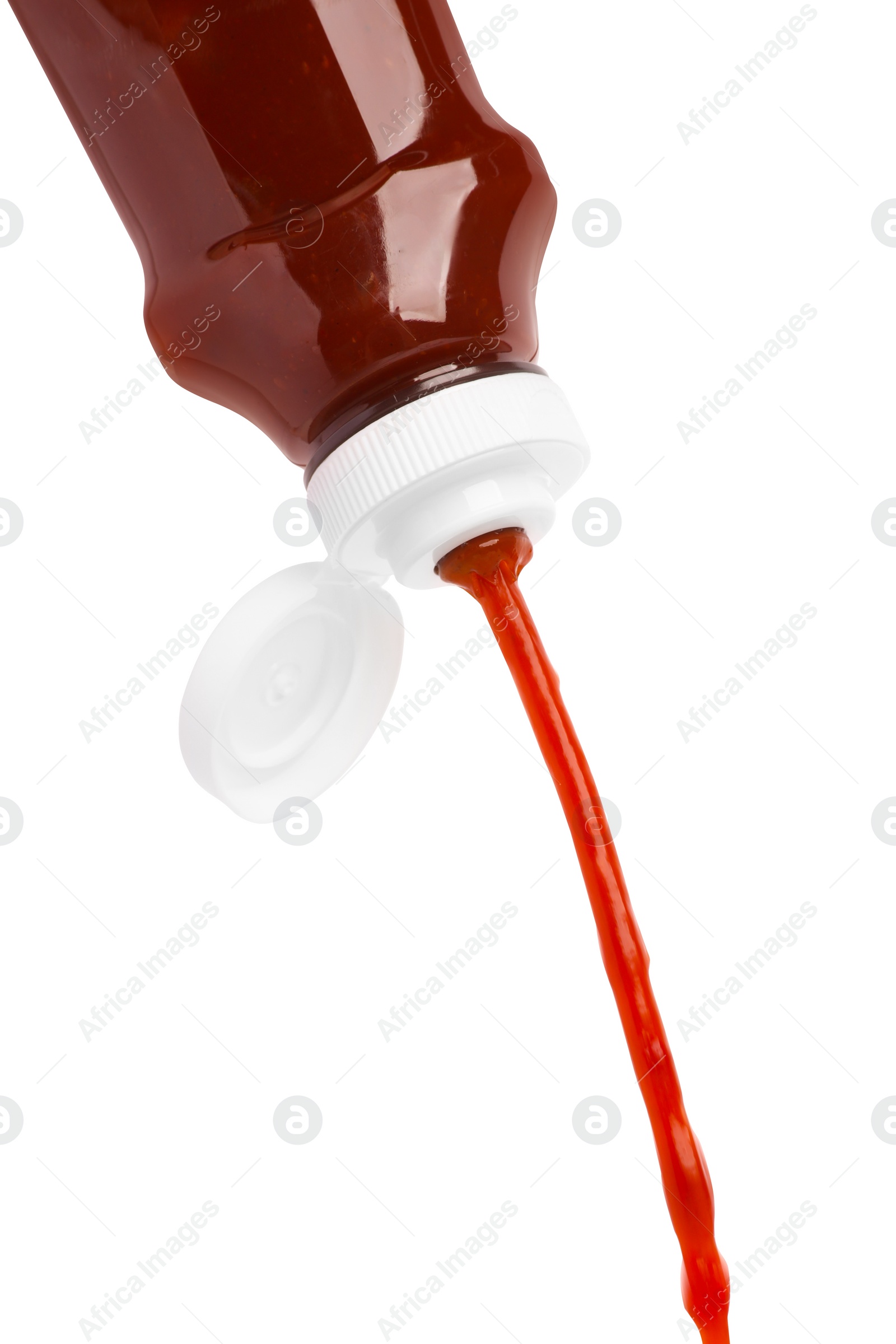 Photo of Pouring tasty red ketchup from bottle isolated on white