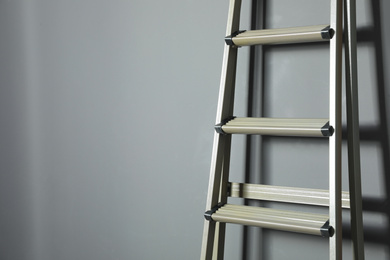 Metal stepladder on grey background, closeup. Space for text