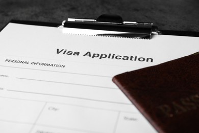 Photo of Visa application form for immigration and passport on grey table, closeup