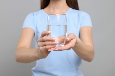 Photo of Healthy habit. Closeup of woman holding glass with fresh water on grey background