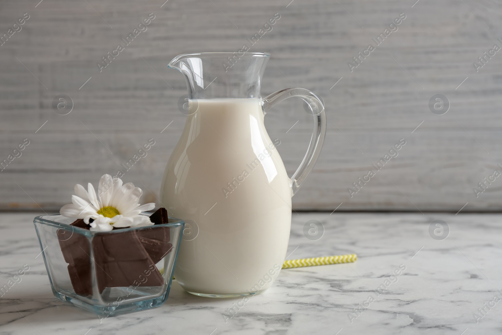 Photo of Jug with milk and chocolate pieces on table