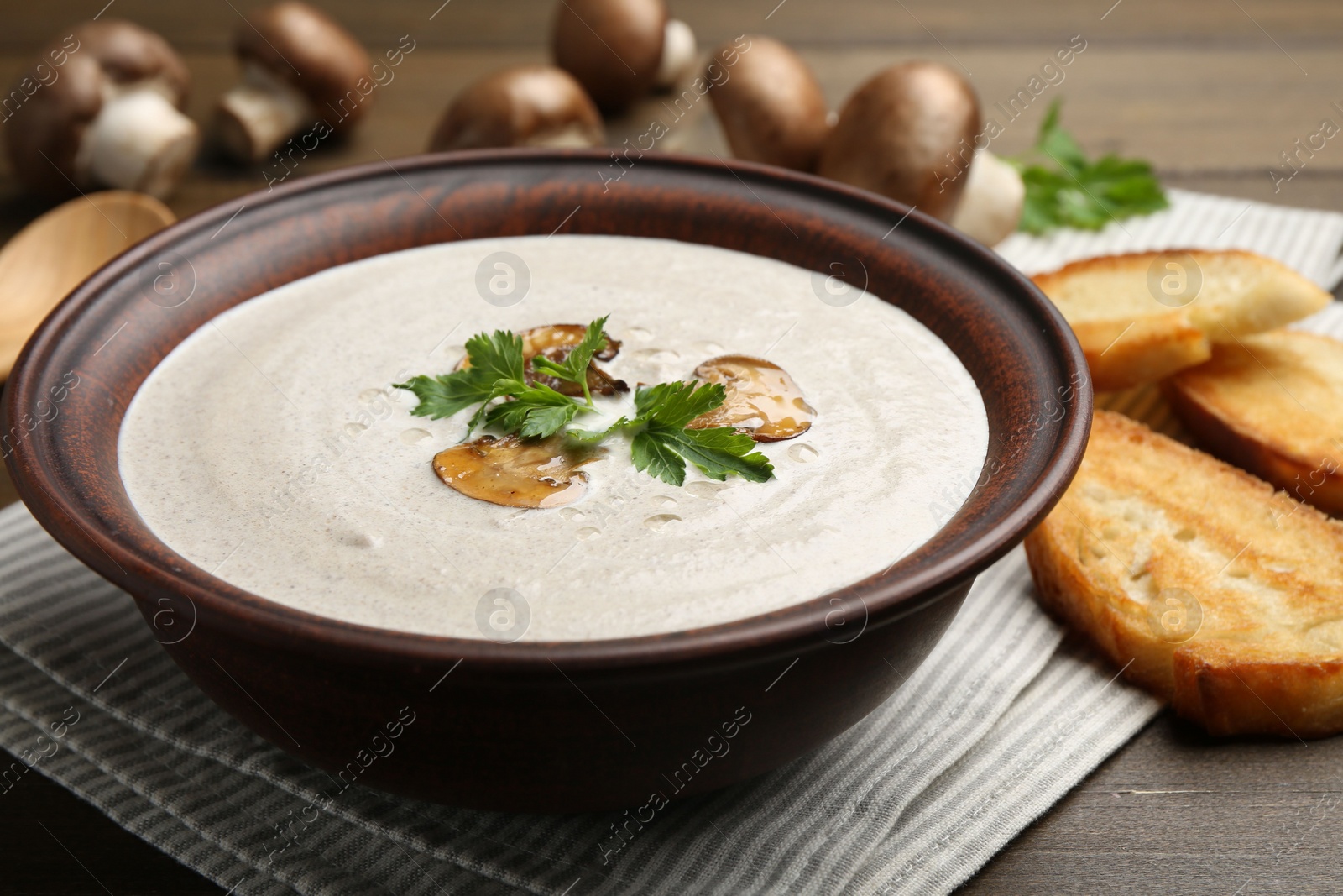 Photo of Fresh homemade mushroom soup in ceramic bowl on wooden table