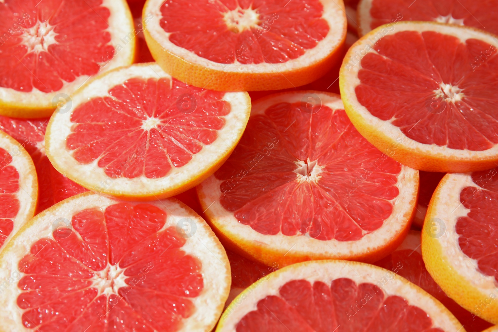 Photo of Many sliced fresh ripe grapefruits as background, closeup