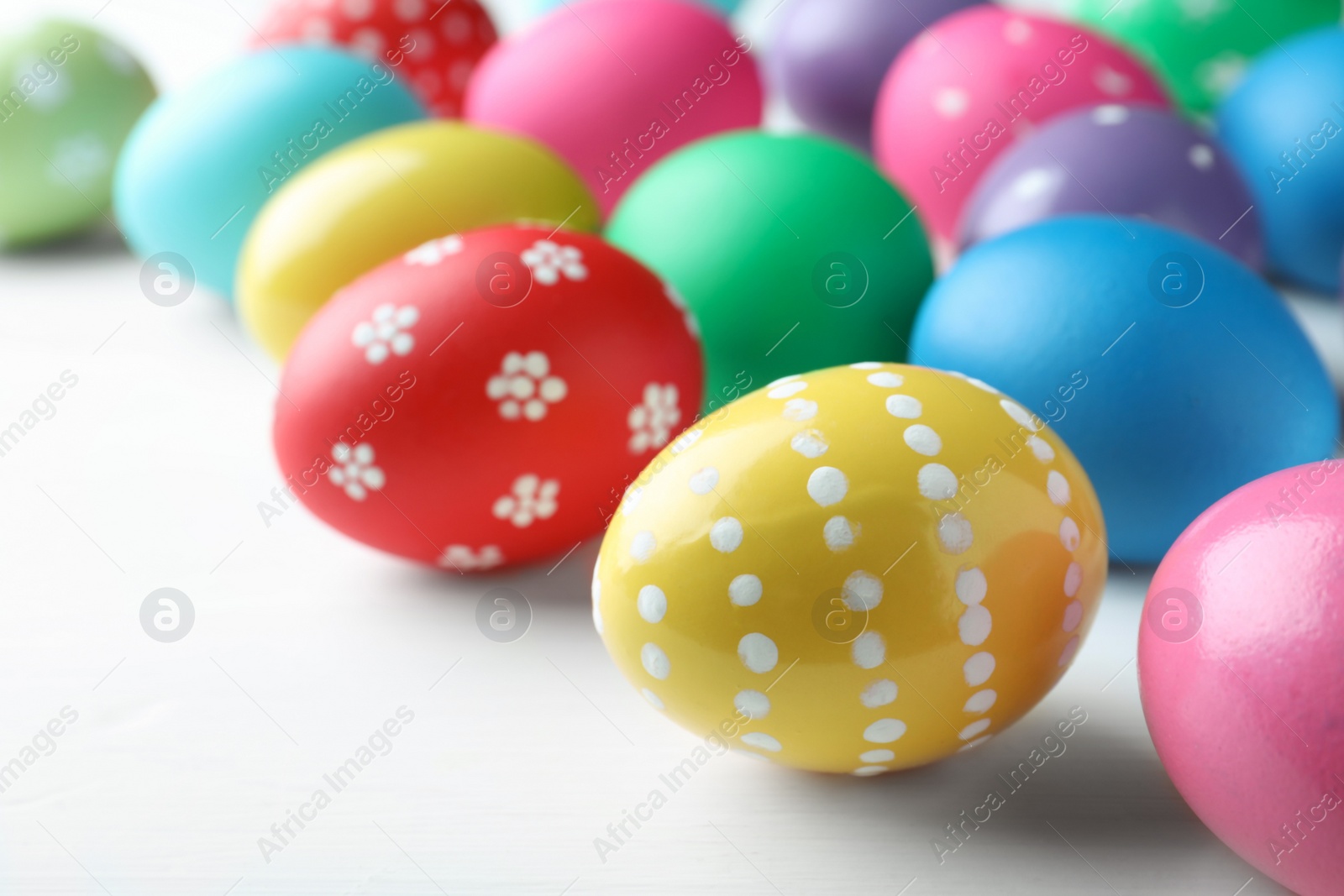 Photo of Bright painted eggs on white wooden table, closeup. Happy Easter