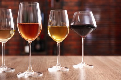 Different tasty wines in glasses on wooden table