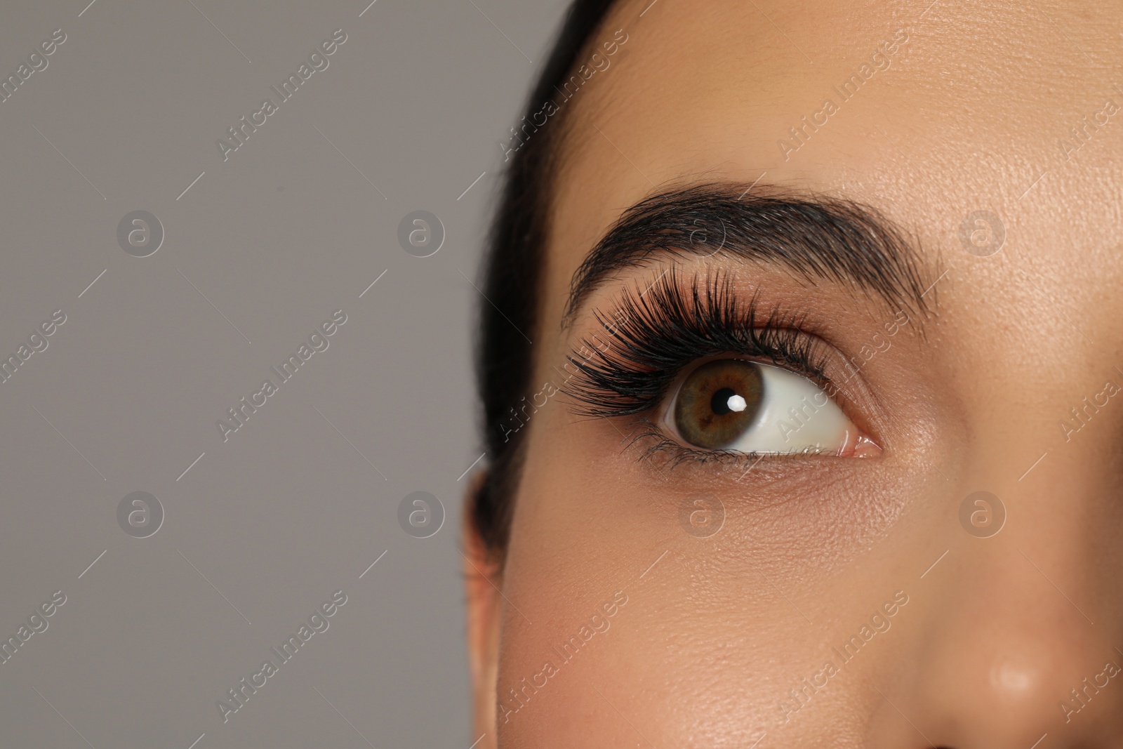 Photo of Beautiful young woman with long eyelashes on grey background, closeup. Space for text