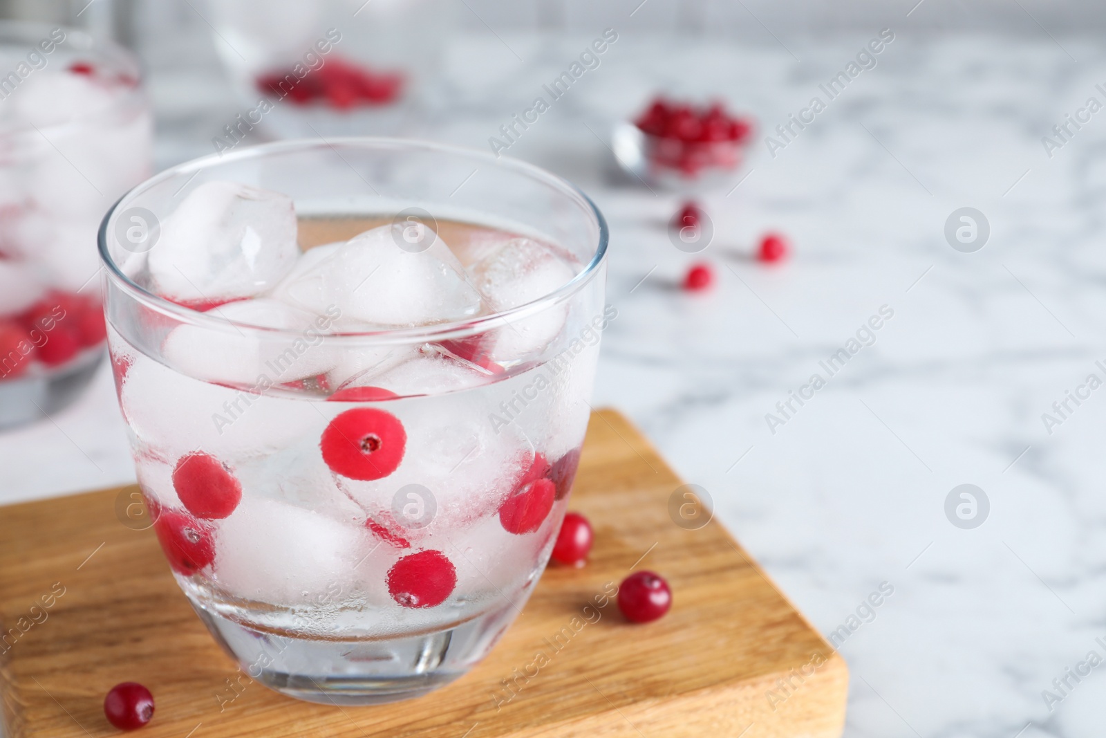 Photo of Glass of cocktail with vodka, ice and cranberry on white marble table. Space for text