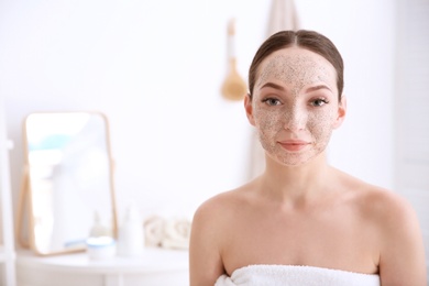 Woman with scrub on face in bathroom