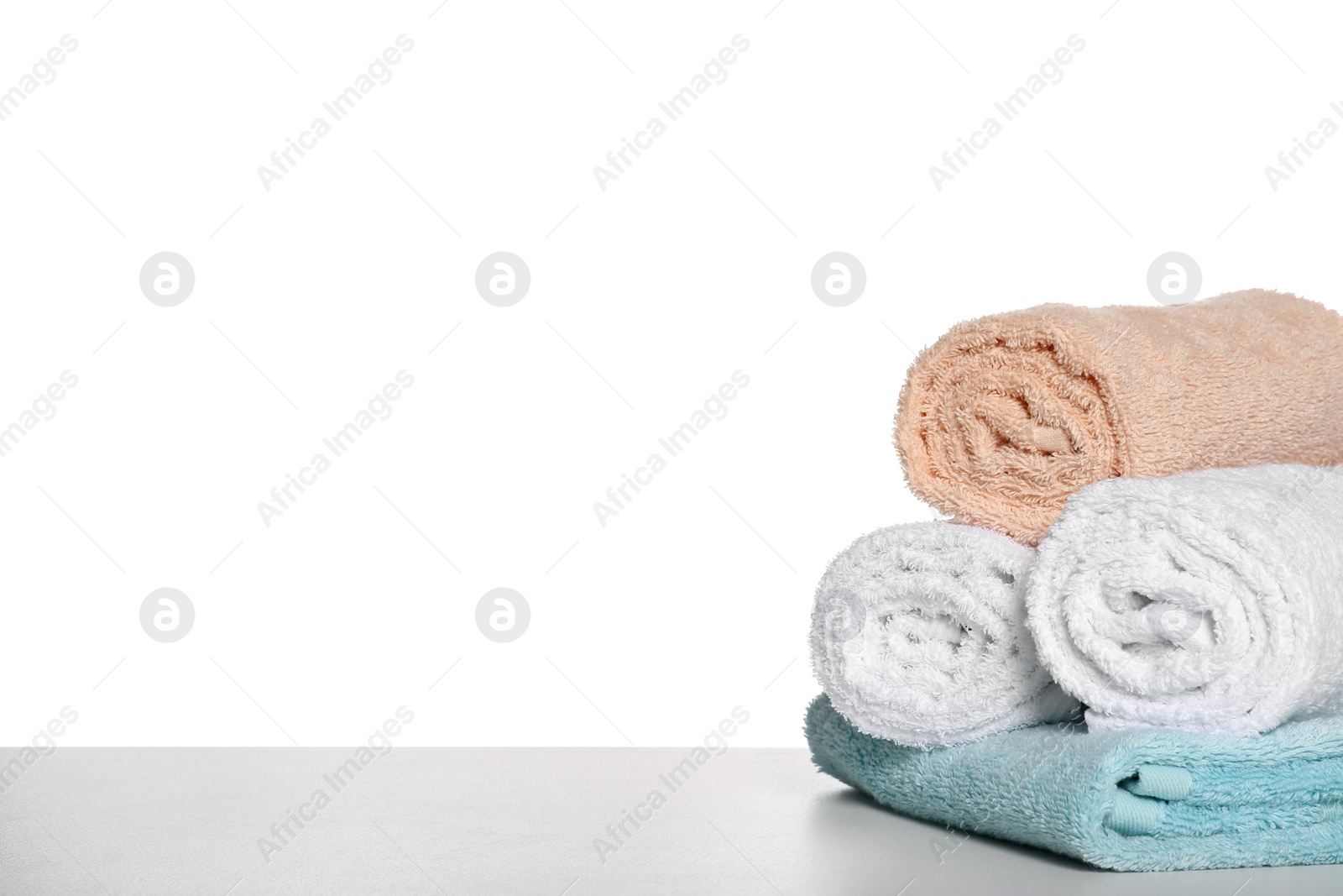 Photo of Soft colorful terry towels on light table against white background, space for text