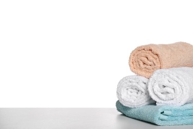 Soft colorful terry towels on light table against white background, space for text