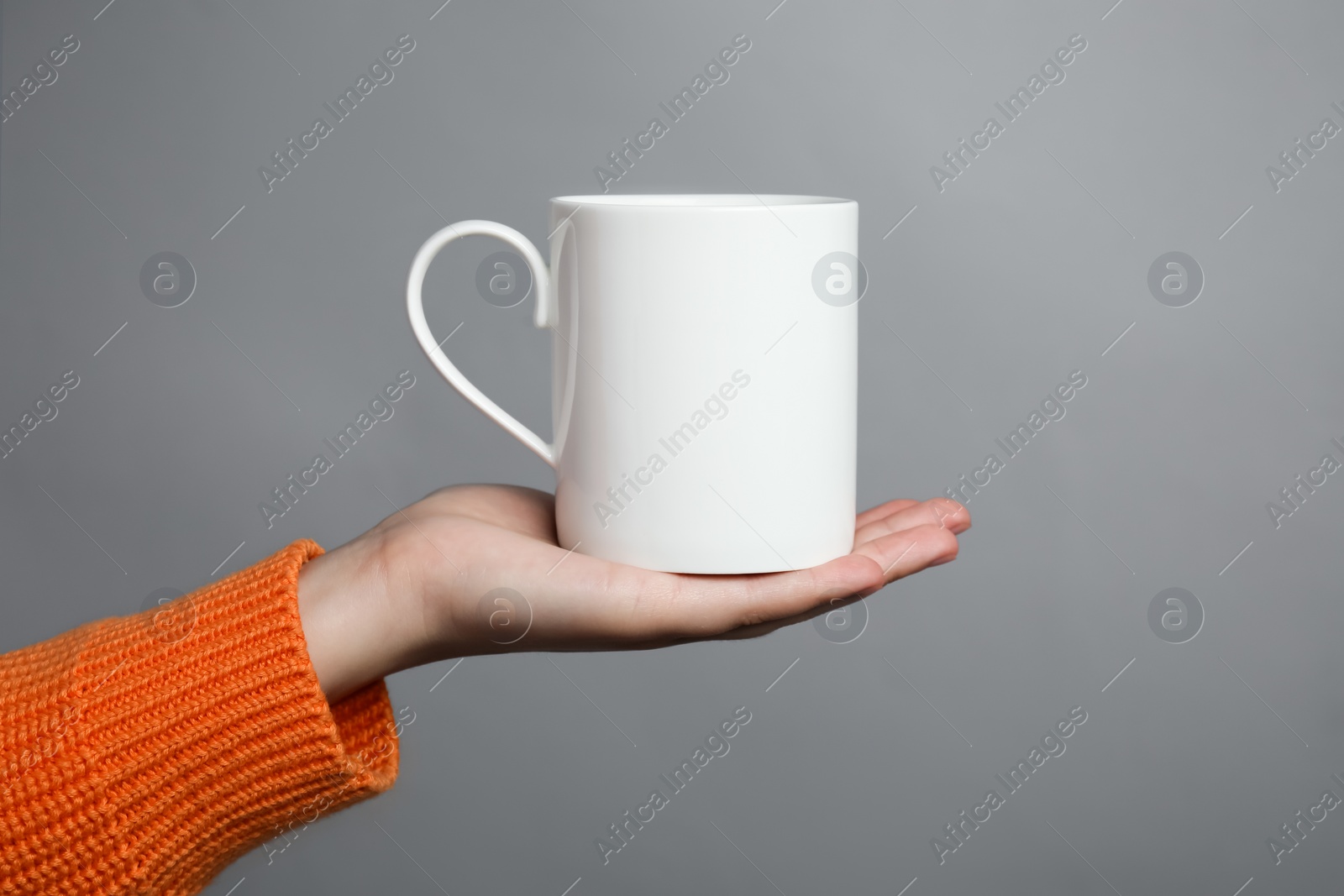 Photo of Woman holding white mug on light grey background, closeup