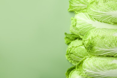 Many fresh Chinese cabbages on pale green background, top view. Space for text