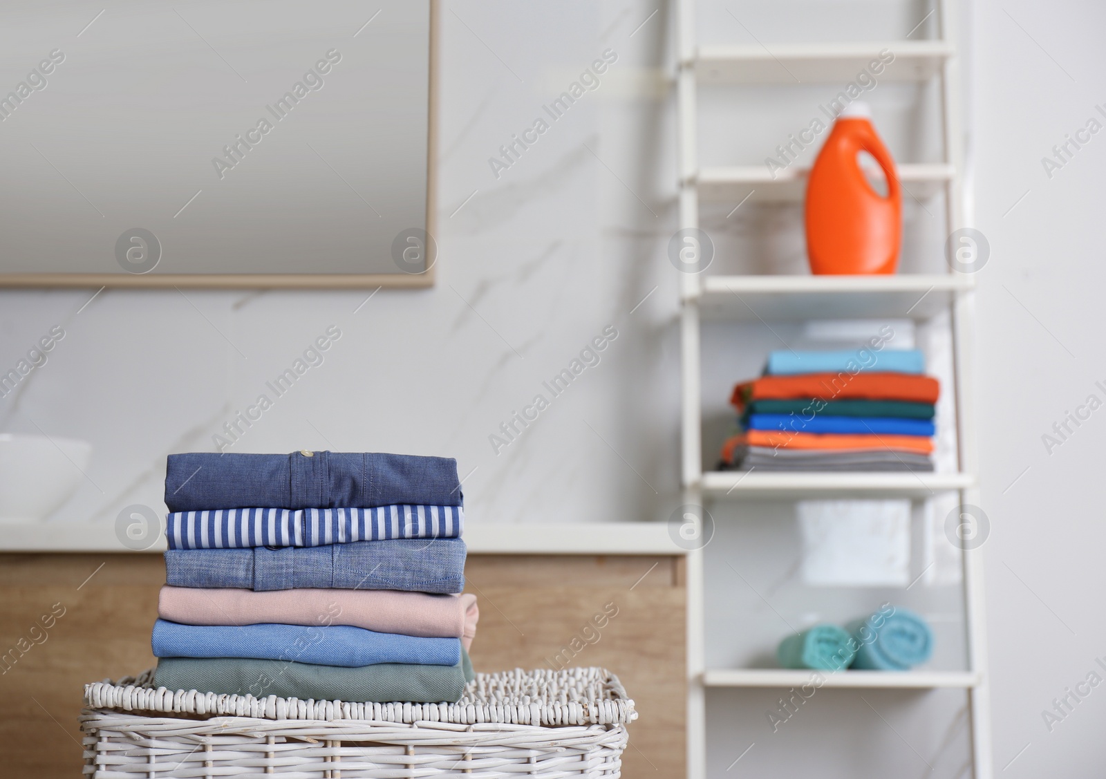 Photo of Stack of fresh laundry on basket in bathroom