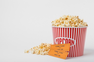 Photo of Bucket of fresh popcorn and tickets on white background. Cinema snack