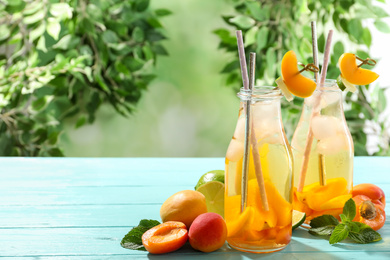 Photo of Delicious refreshing drink with apricot on light blue wooden table. Space for text