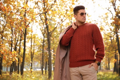 Handsome man walking in park on autumn day