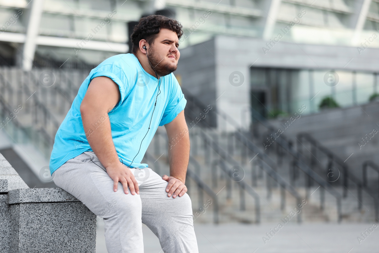 Photo of Young overweight man in sportswear resting outdoors