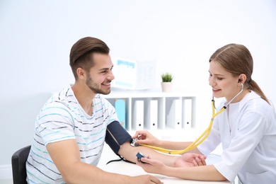 Doctor checking young man's pulse in hospital