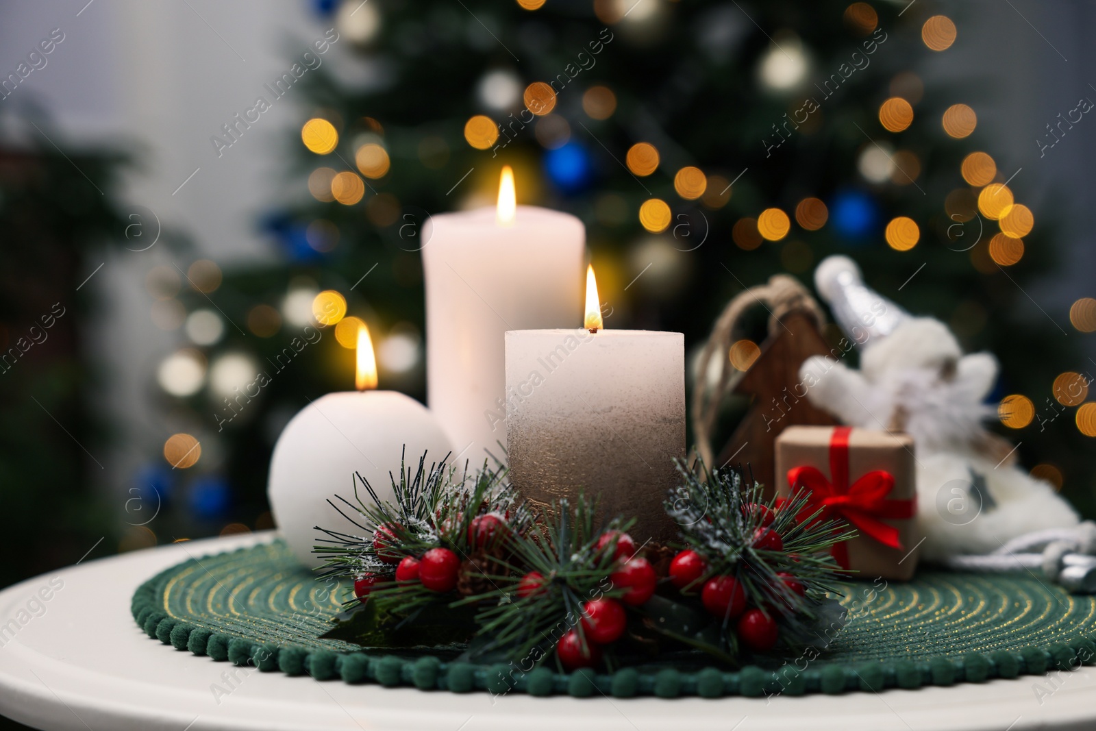 Photo of Beautiful burning candles and Christmas decor on white table indoors