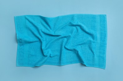 Photo of Crumpled soft beach towel on light blue background, top view