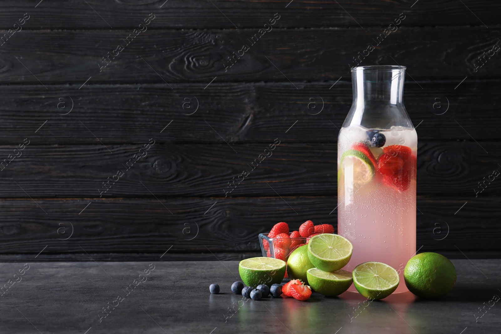 Photo of Natural lemonade with berries in bottle on table