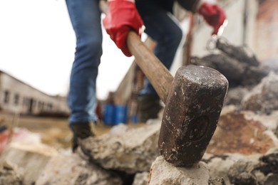 Photo of Man breaking stones with sledgehammer outdoors, selective focus