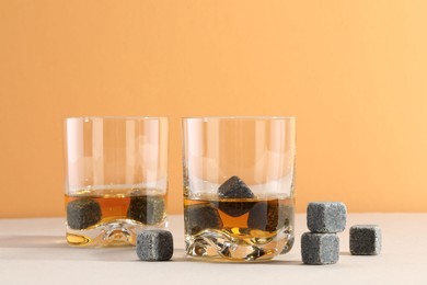 Whiskey stones and drink in glasses on light table