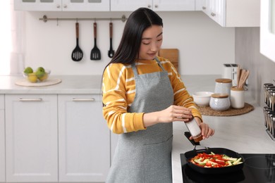 Beautiful woman cooking vegetable dish in kitchen. Space for text