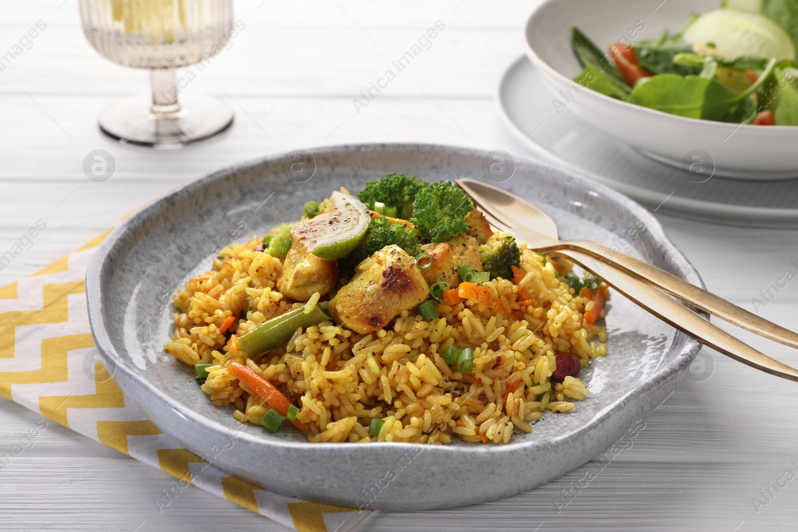 Photo of Tasty rice with meat and vegetables in plate served on white wooden table, closeup