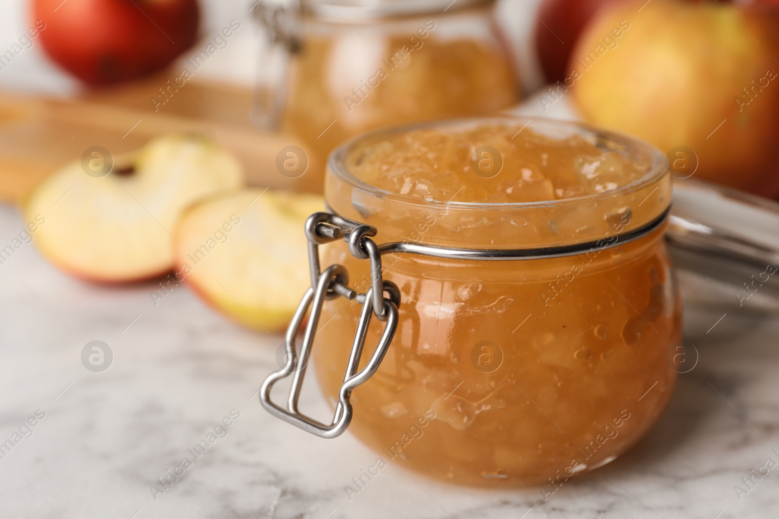 Photo of Delicious homemade apple jam on marble table