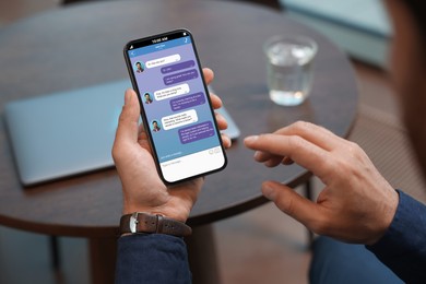 Man texting via mobile phone indoors, closeup. Device screen with messages