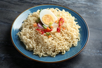 Photo of Plate of tasty noodles with egg and vegetables on marble background