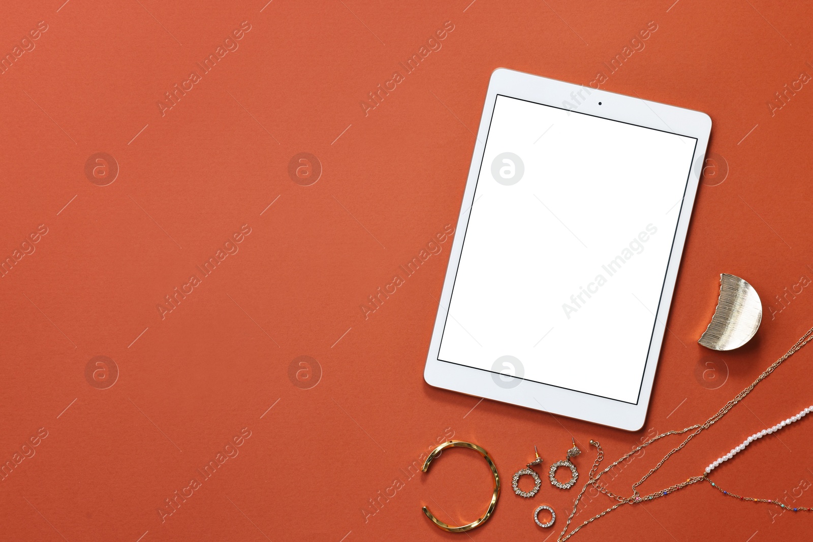 Photo of Modern tablet and bijouterie on color background, flat lay. Space for text