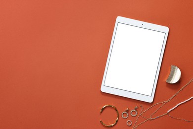 Photo of Modern tablet and bijouterie on color background, flat lay. Space for text