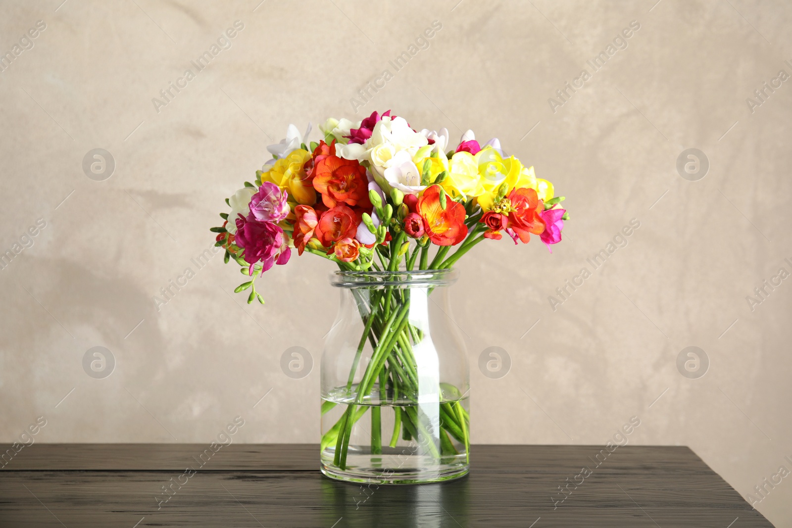 Photo of Bouquet of spring freesia flowers in vase on table