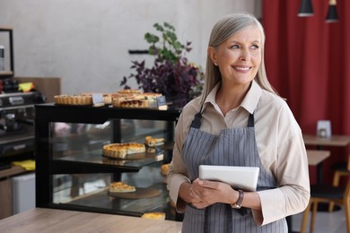 Photo of Happy business owner with tablet in her cafe, space for text