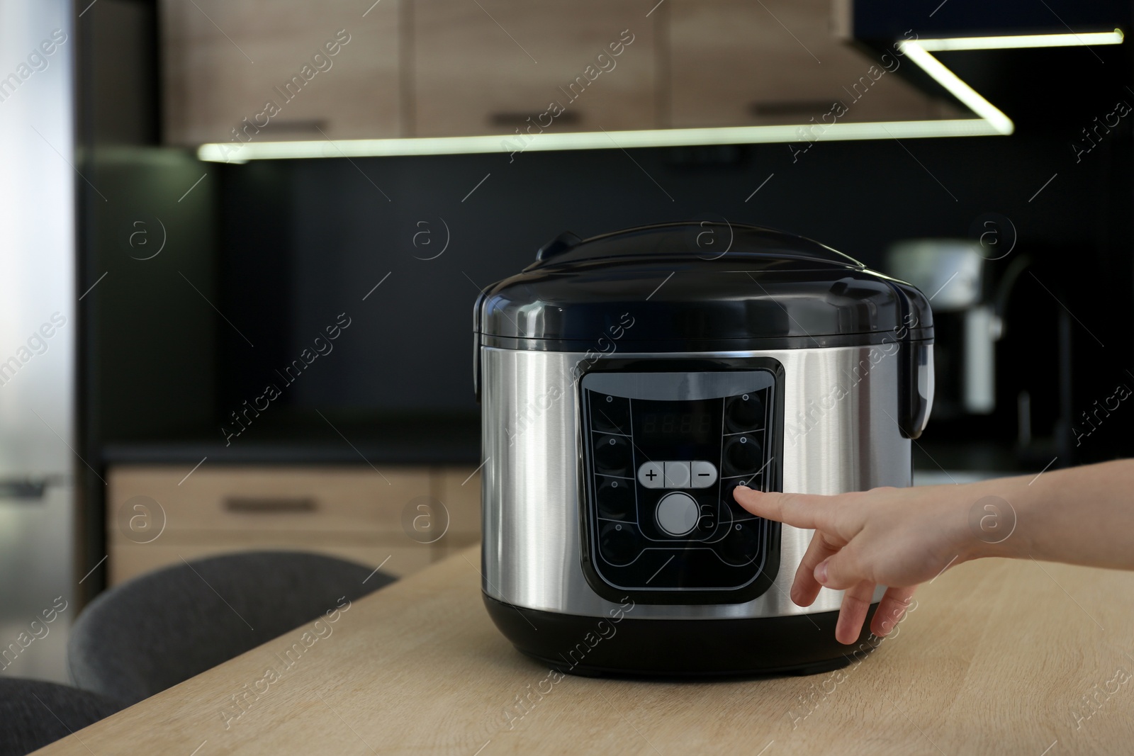 Photo of Woman turning on modern electric multi cooker in kitchen, space for text