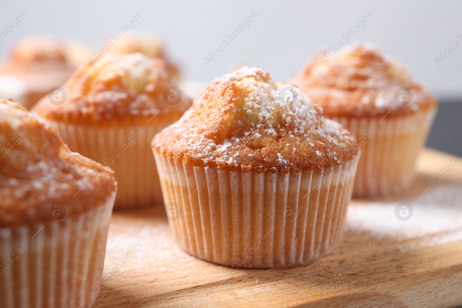 Photo of Delicious sweet muffins on wooden board, closeup