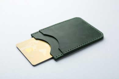 Woman holding leather card holder with credit card on light grey background