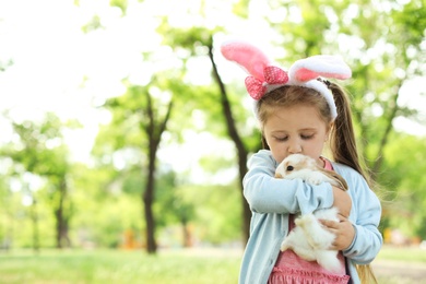 Little girl with adorable bunny outdoors on sunny day. Easter celebration