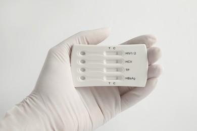 Photo of Doctor holding disposable express test for hepatitis on white background, closeup