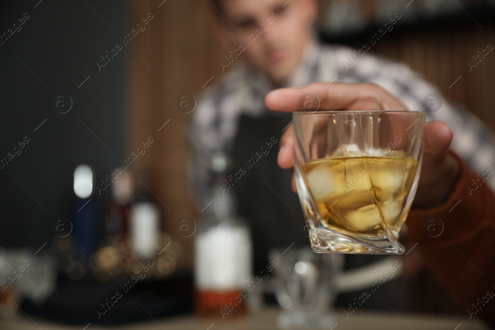 Photo of Young man with glass of whiskey in bar, closeup. Space for text